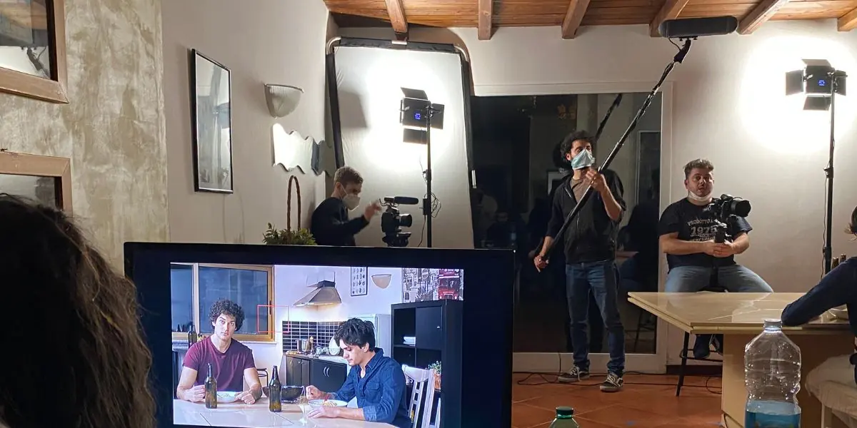 Una troupe al lavoro sul set, fra luci, monitor e microfono